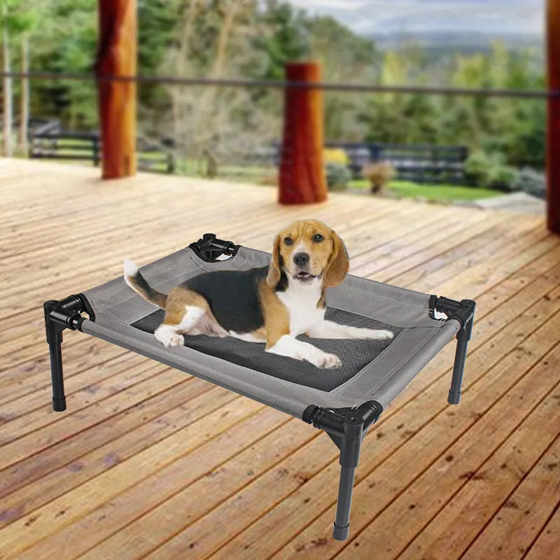 Black Oxford cloth outdoor dog bed with steel frame, shown on grass for camping use.