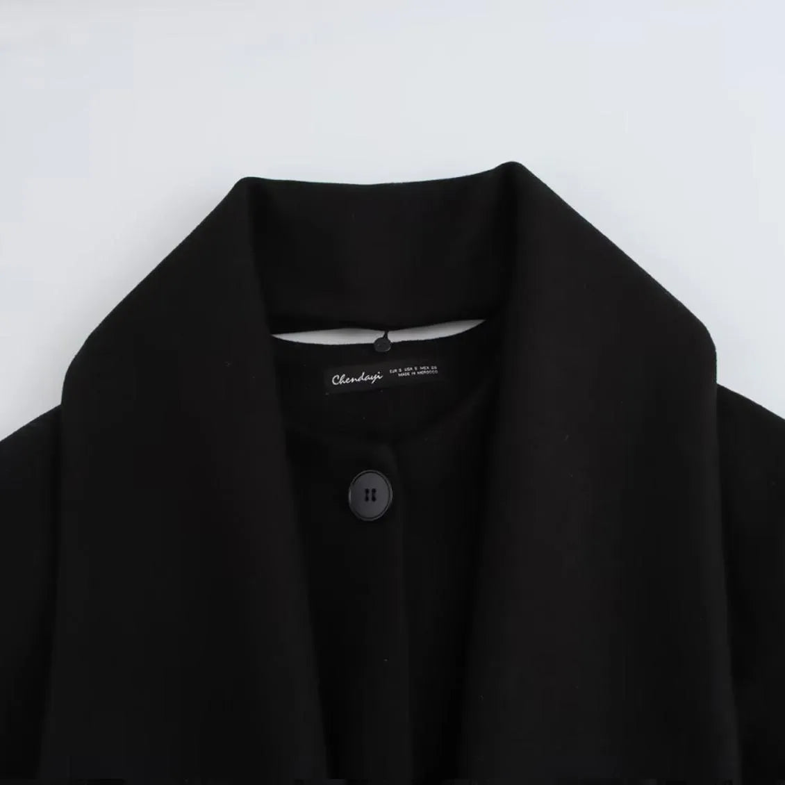 A woman wearing a longline black polyester coat with a detachable faux fur collar.