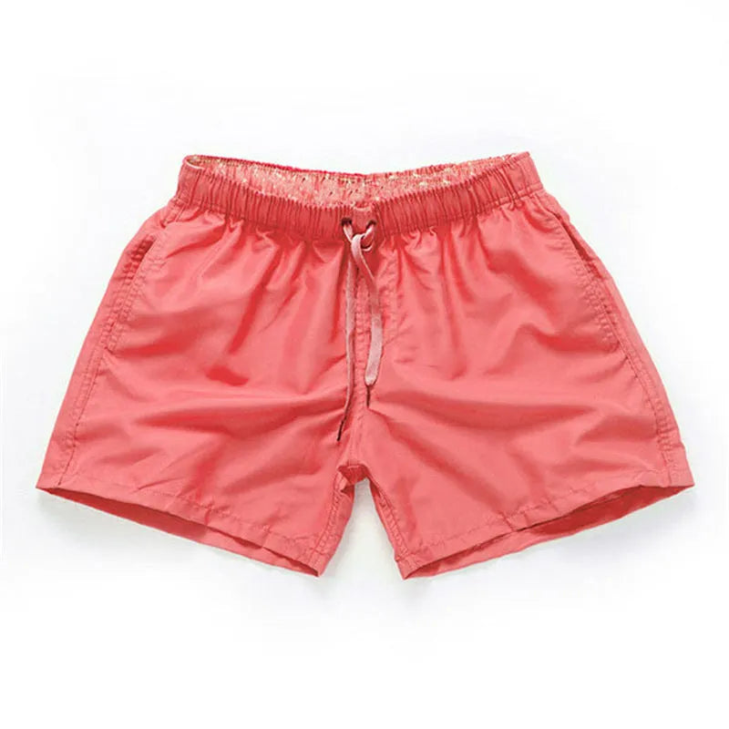 Men's straight-leg polyester surf shorts on a beach, available in multiple colours including fluorescent yellow and black.