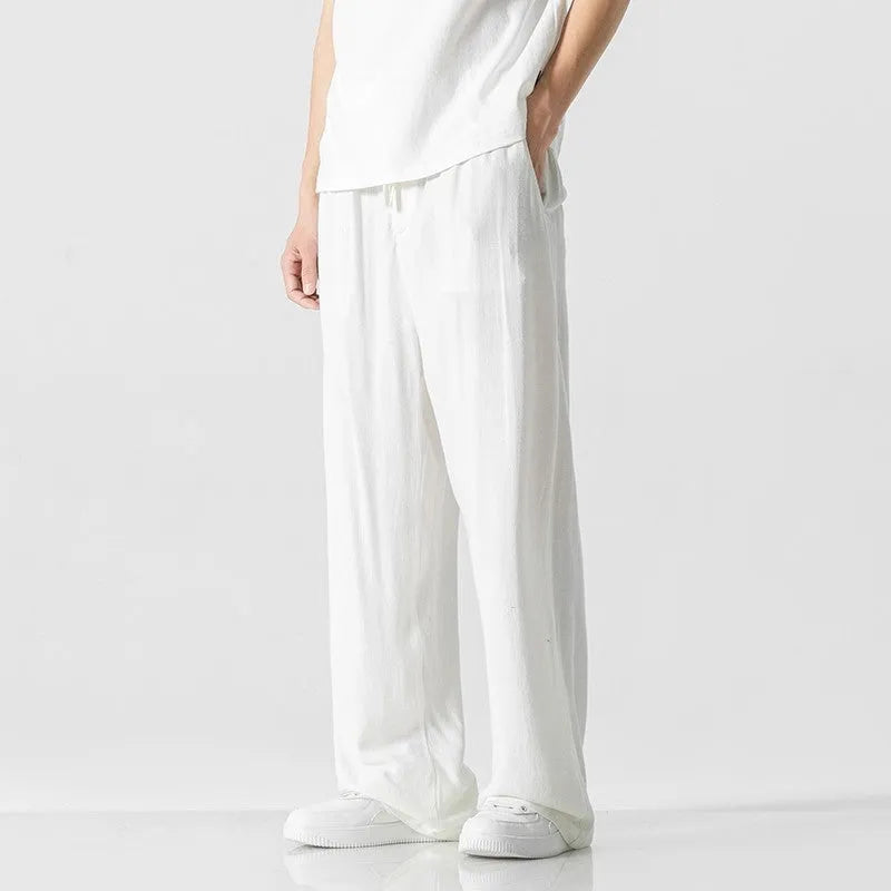 Man wearing beige loose-fit straight-leg cropped trousers with a drawstring waist.