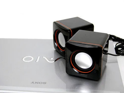 Black square USB-powered 2.0 desktop computer speaker on a desk.