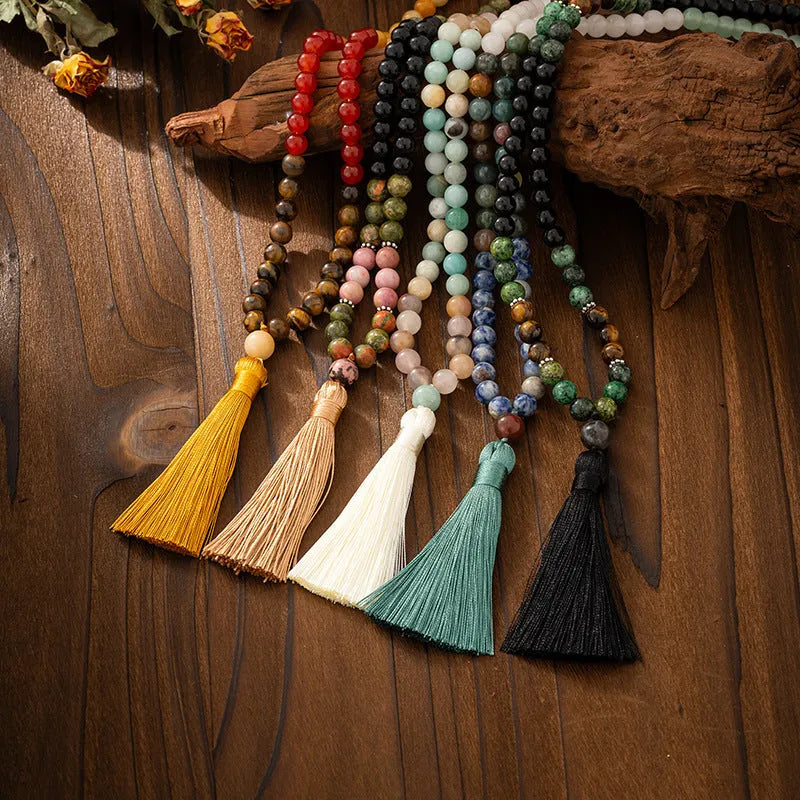 Vintage bohemian style long necklace with natural stone beads, geometric chain, tassel, and matching bracelet on a grey background.