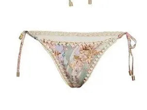 Women's creamy-white floral bikini swimsuit set with matching skirt on beach