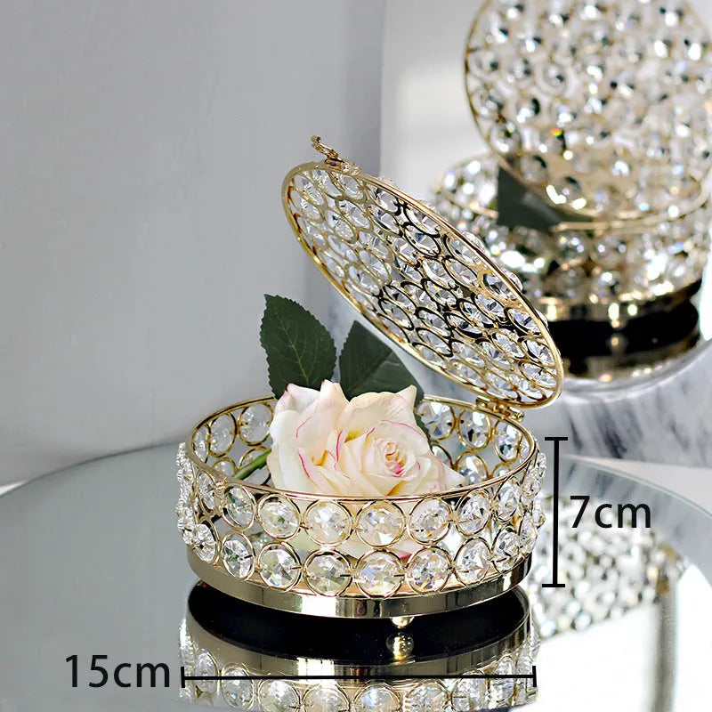 French gold iron jewelry storage box with a clear crystal glass lid on a wooden surface.
