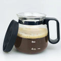 Transparent borosilicate glass stovetop coffee maker with black silicone cover on a hob.