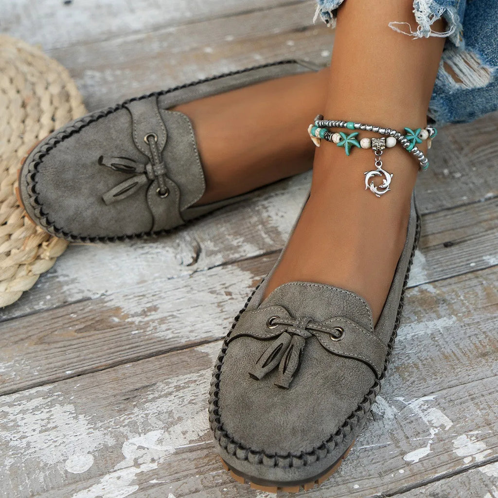 Women's apricot suede flat shoes with a bow detail on the front, showing round toe and low-top design.