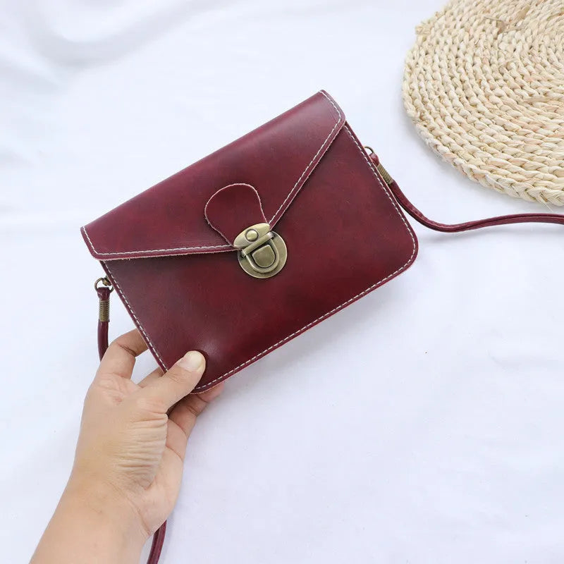 Retro soft surface crossbody messenger bag with flap closure in wine red colour showing internal phone pocket