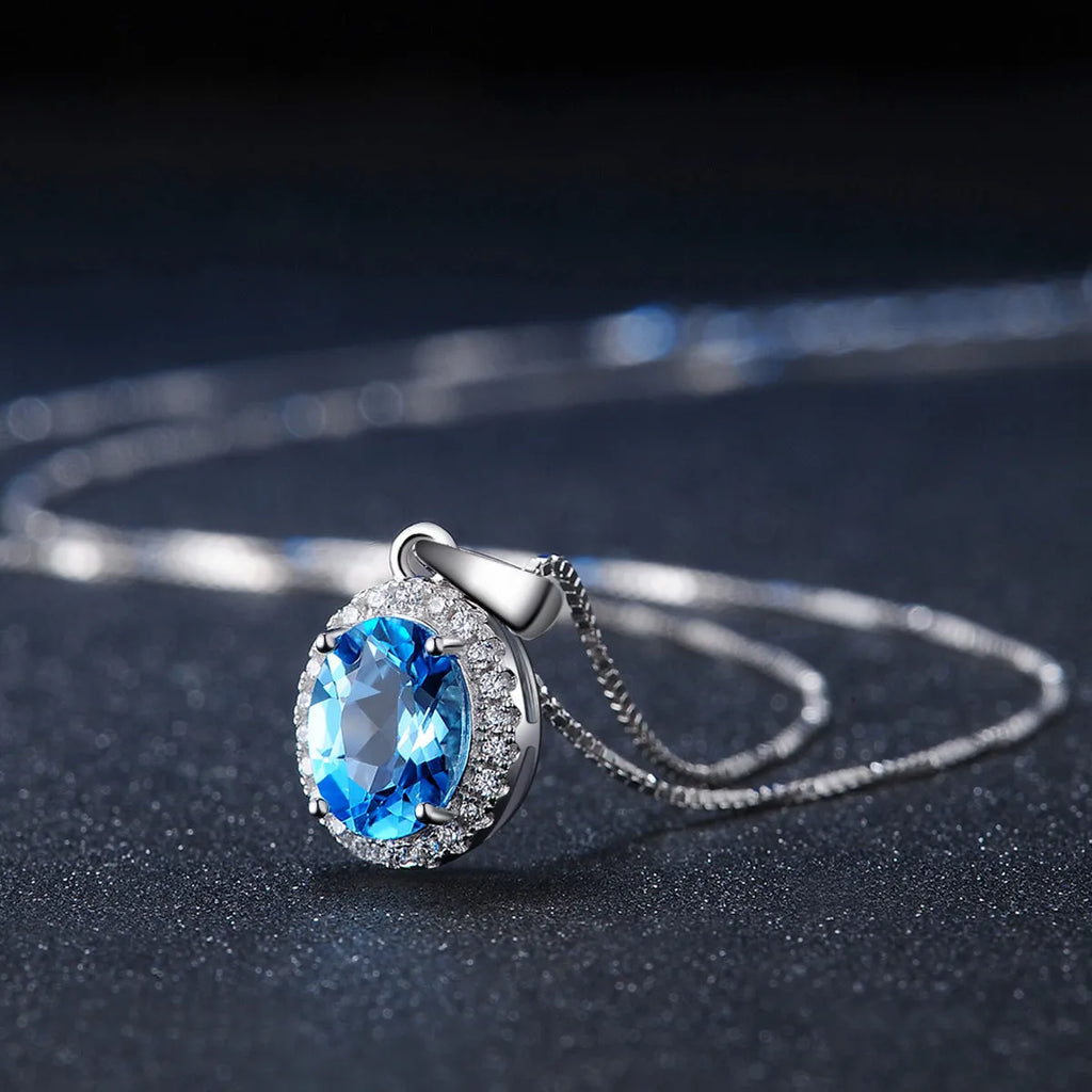 Four-piece sterling silver jewellery set with blue topaz gems showing geometric necklace, earrings, ring, and pendant
