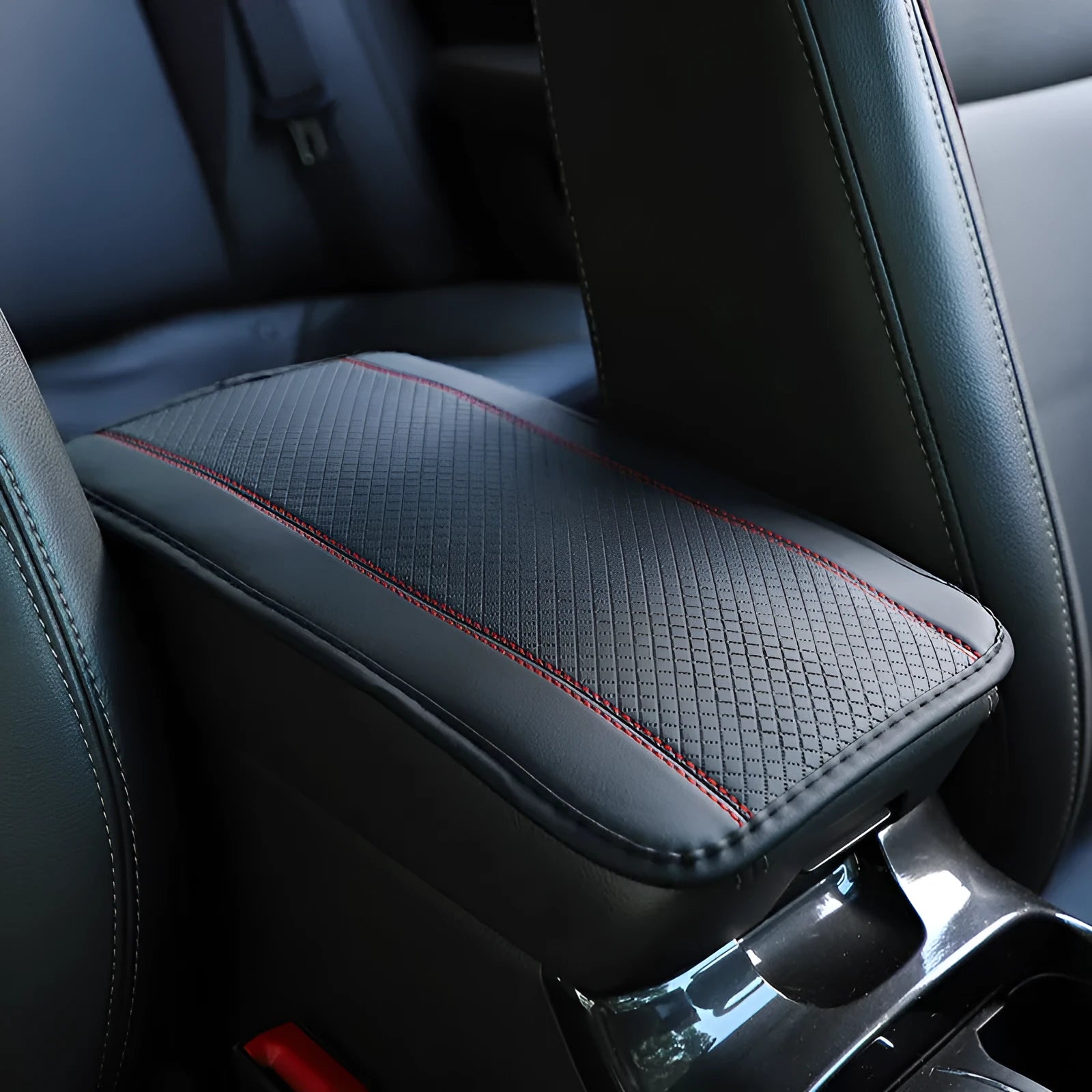Embossed fibre leather car armrest box cushion measuring 32cm by 19cm in black with red trim