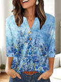 Women's loose-fit V-neck top with a colourful 3D effect pattern, shown in a casual setting.