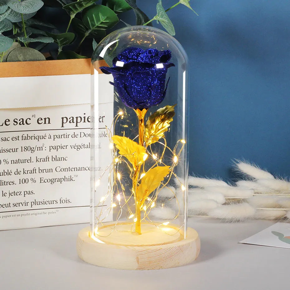Glass dome containing red eternal roses illuminated by a warm white bendable LED light string.