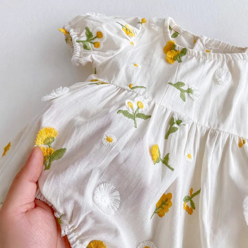 Apricot cotton baby romper with embroidered sunflower, short sleeves, triangle jumpsuit shape and hidden hook closure.