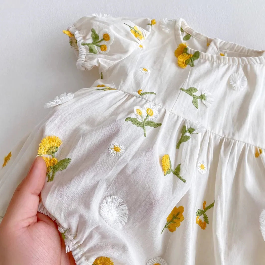 Apricot cotton baby romper with embroidered sunflower, short sleeves, triangle jumpsuit shape and hidden hook closure.