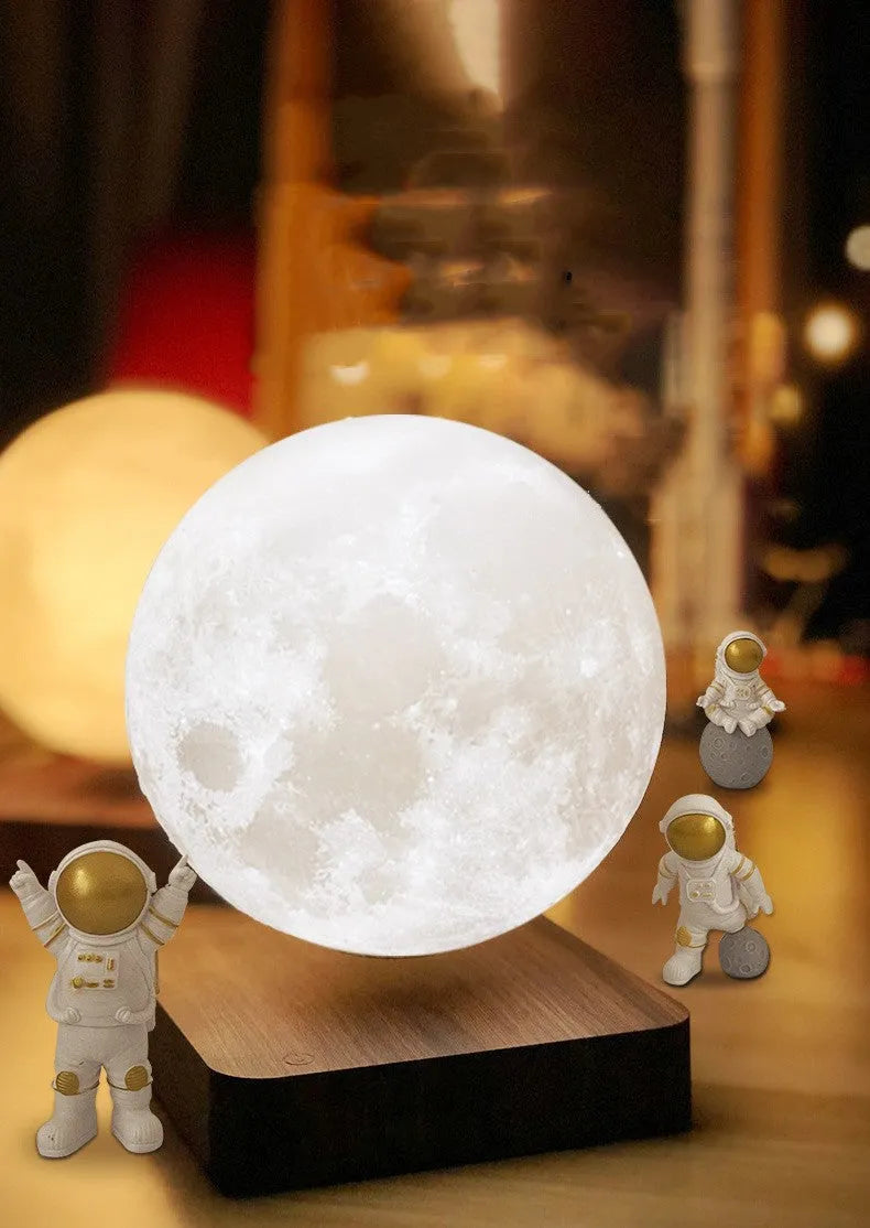 Maglev floating moon planet night light with three astronaut figurines on a dark surface.