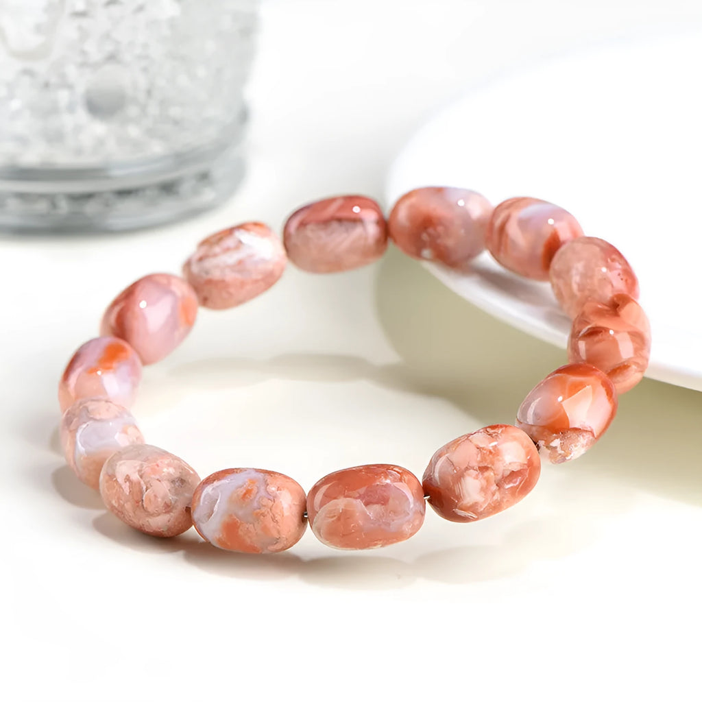 Natural cherry agate barrel bead bracelet with Ruyi symbol on a wrist.