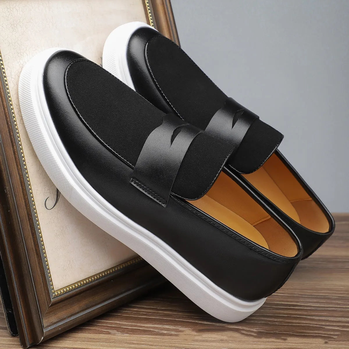 Black men's slip-on loafers with tassel detail and rubber sole, shown in profile view