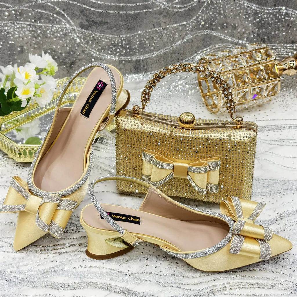 Women's black pointed toe sandals with a mid heel and matching rhinestone bag on a white background.