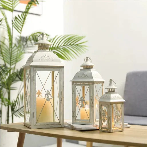 Black and white wrought iron floor standing storm lantern with tempered glass panels on a patio.