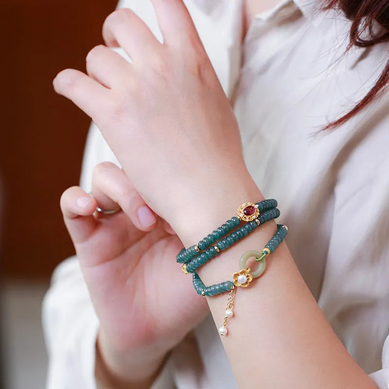 Close-up of a blue water jade and abacus bead bracelet with tourmaline rings and freshwater pearls.