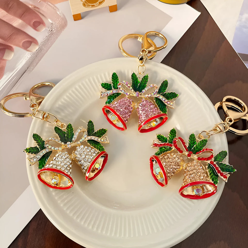 Diamond studded Christmas bell shaped keychain in metal, white diamond colour, on a festive background