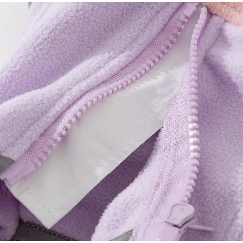 Small dog wearing a colour-block fleece jumpsuit in purple and pink, with full-zip front and leash ring