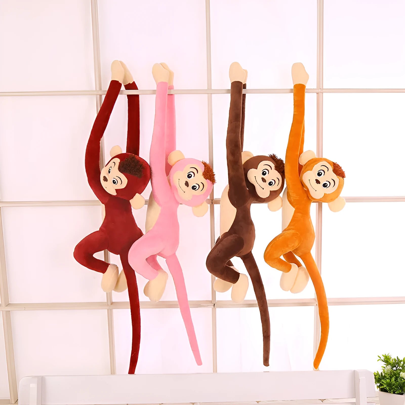 Long-armed pink plush monkey toy hanging from a curtain rod