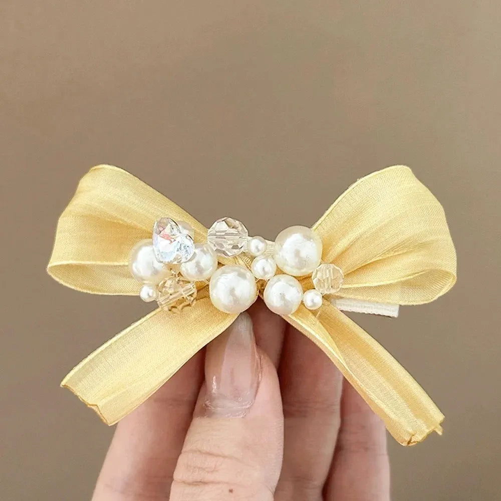Yellow cloth bow hair barrette with rhinestone and pearl decoration on duckbill clip