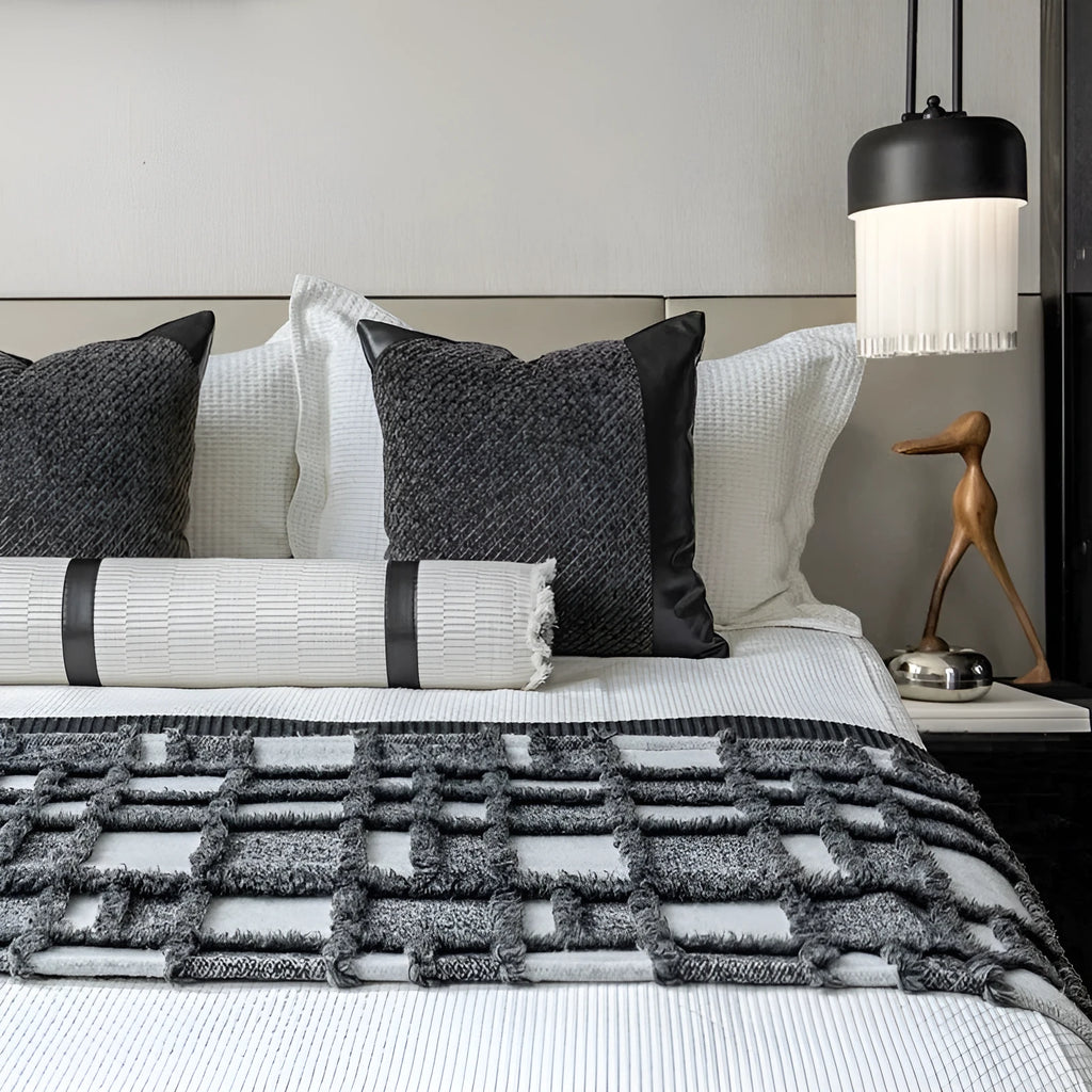 Modern minimalist grey and white plaid bed runner blanket set with a leather round pillow on a bed.