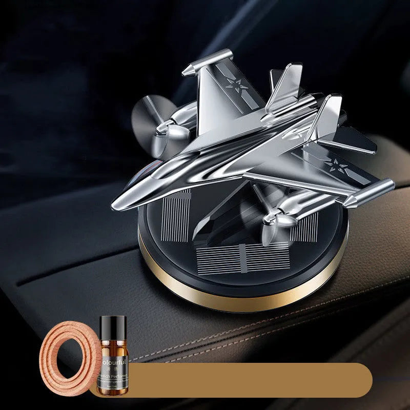 Silver solar-powered rotating fighter jet perfume ornament on a surface.