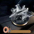 Silver solar-powered rotating fighter jet perfume ornament on a surface.