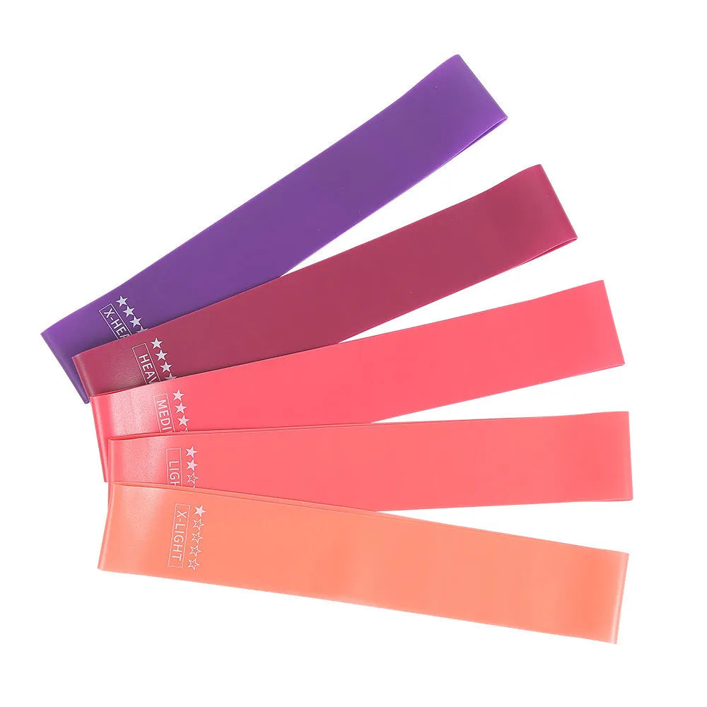 Yoga hip resistance band set in six colours from 0.4mm green to 1.2mm black laid flat on a surface
