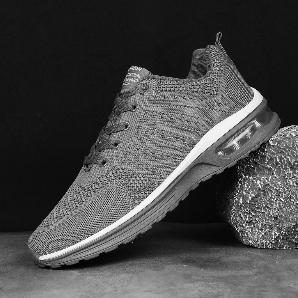Pair of grey and black Flyknit mesh running shoes with a round toe and PU sole on a white background.