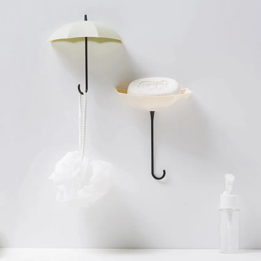 3 plastic umbrella-shaped sticky hooks in Nordic pink blue green, on a white door, holding keys