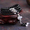 Black agate beaded bracelet with 108 geometric beads and number elements on wrist