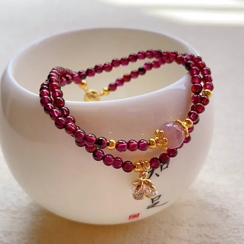 Close-up of a handmade women's natural garnet double ring bracelet in garnet colour.