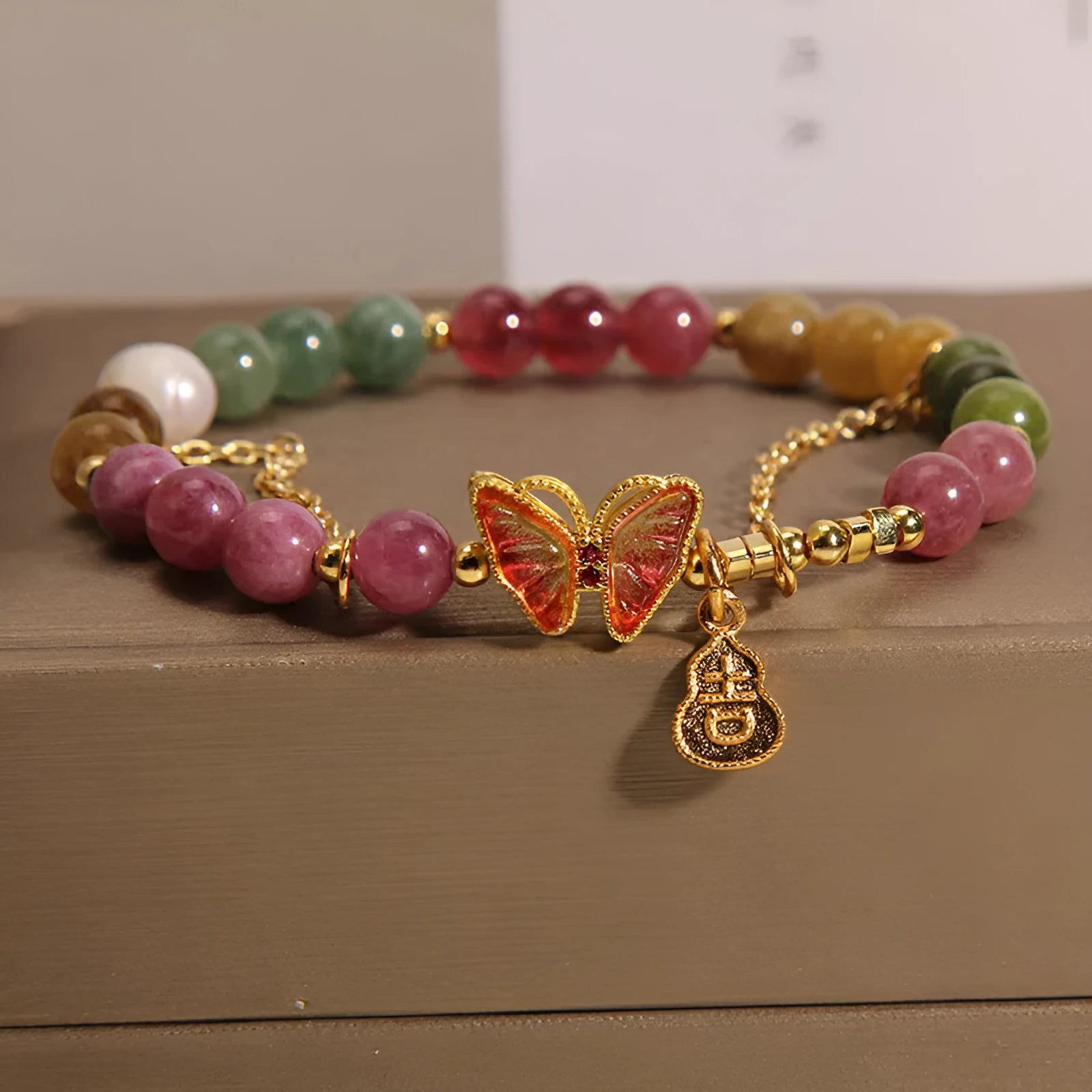 Close-up of a women's agate bracelet with a tourmaline butterfly gourd pendant in natural jade colour.