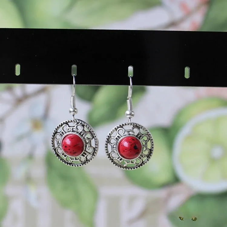 Handmade Miao silver retro earrings with turquoise flower disk and ethnic patterns in black.