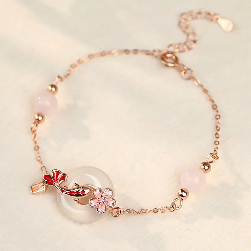 Close-up of a sterling silver bracelet with white chalcedony stones in a koi design on a wrist.