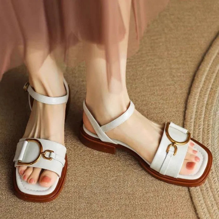 Women's black thick-soled leather sandals with a round toe and button closure on a white background.
