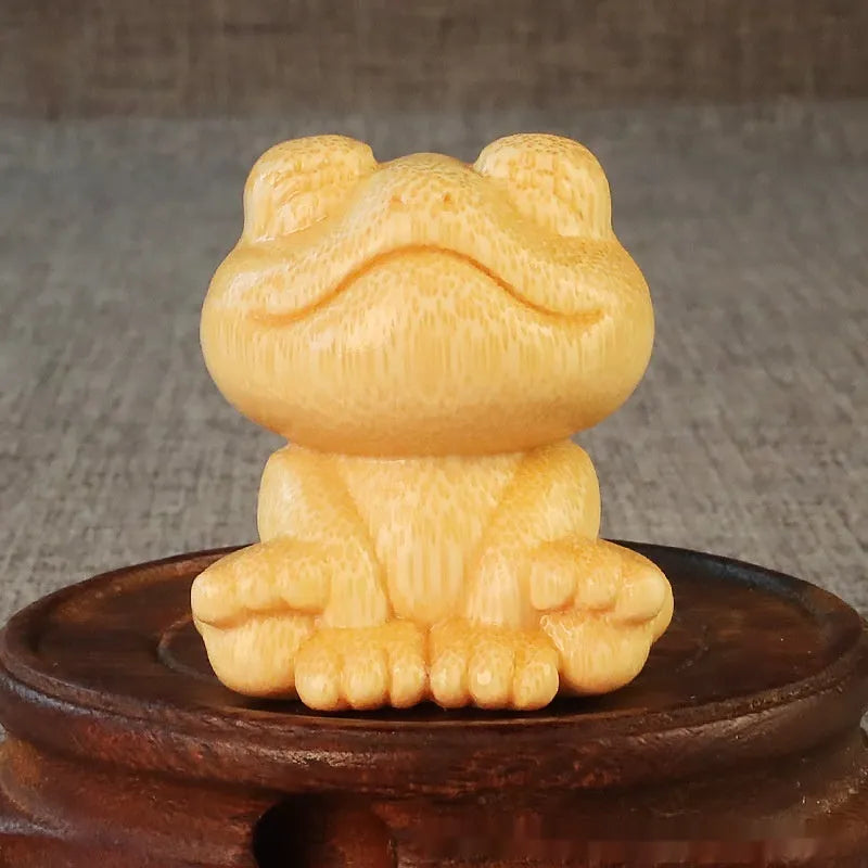 Small smiling frog ornament carved from solid bamboo on a plain background.