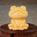 Small smiling frog ornament carved from solid bamboo on a plain background.