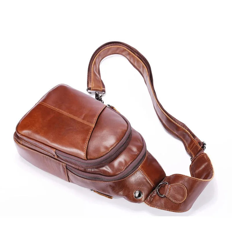 Men's brown cowhide leather crossbody bag with visible stitching and zip closure laid flat on a surface