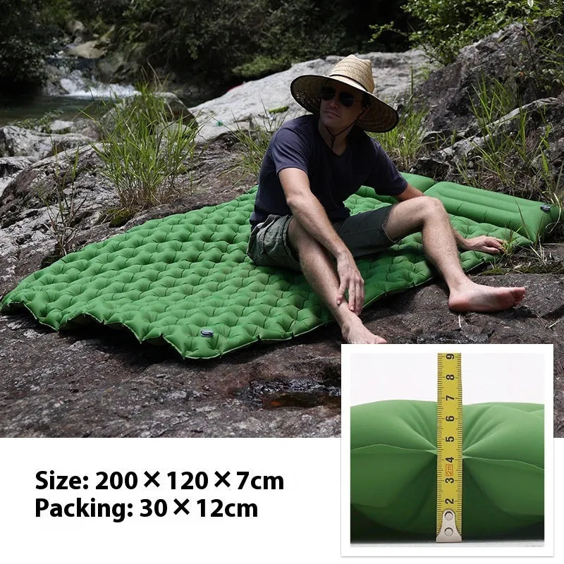 Double size inflated air mattress in army green colour with an attached pillow, on a grass surface.