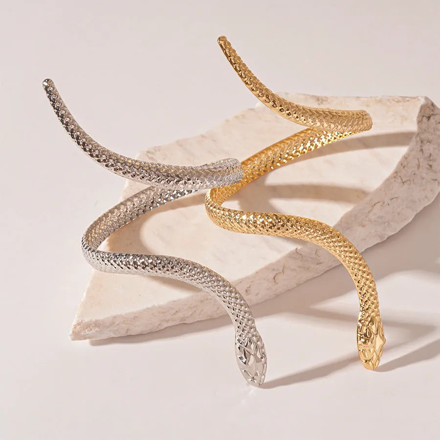 Gold exaggerated twisted winding open snake ring and bracelet jewellery set on white background.