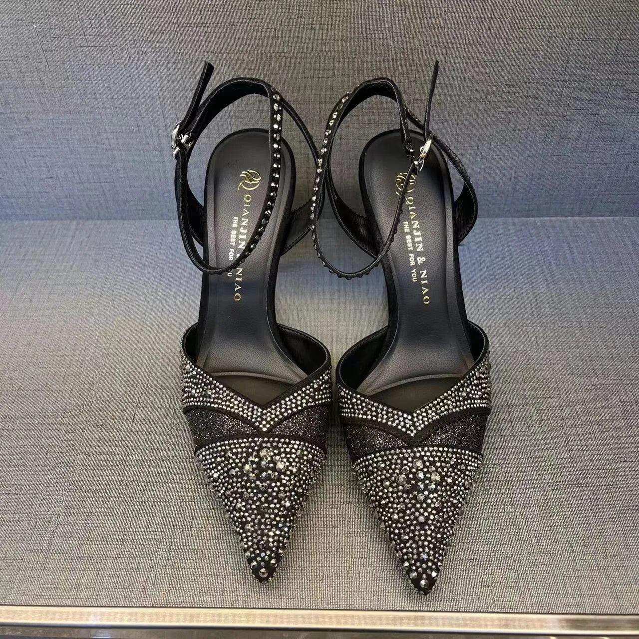 Women's black high heels with hollow design, red sole, and pointed toe on stiletto heel