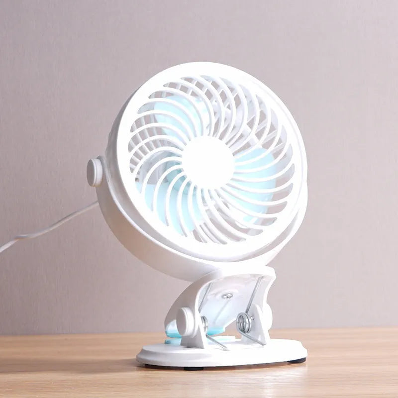 Mini USB desk fan with clip attachment and three blades, shown in desktop setting.