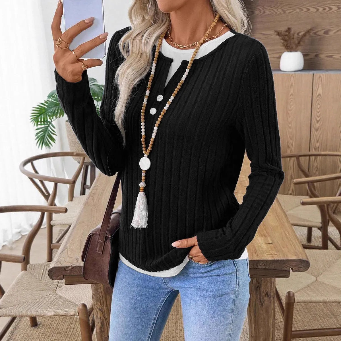 Women's black fake two-piece pullover sweater with round neck button and long sleeves on a model.