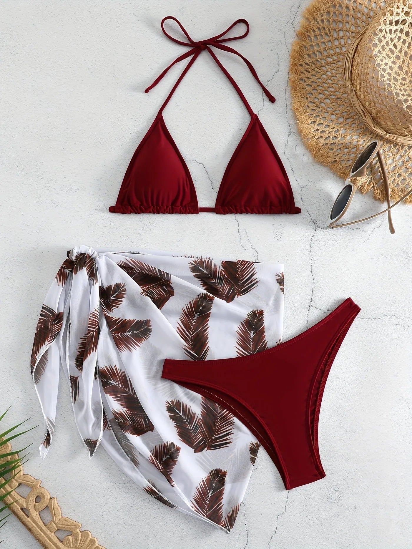 Orange three-piece bikini swimsuit set with a matching printed gauze skirt laid flat.