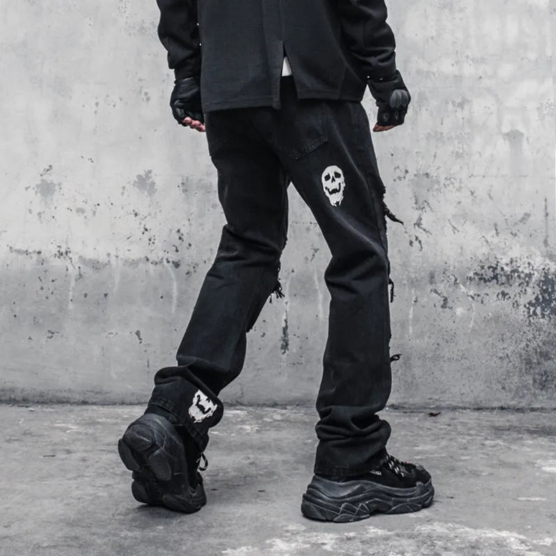 Black cotton denim jeans with skull and crossbones distressed design, mid waist, fit flared horn trousers for men.