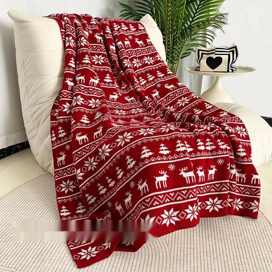 Personalised Christmas blanket with snowflake or reindeer pattern on a sofa.